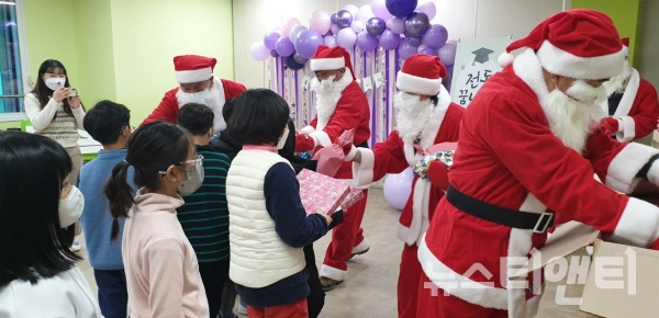 행복산타(세종시 전동면지역사회보장협의체 위원)들이 24일 전동초등학교에서 학생들에게 크리스마스 선물을 전달하고 있다. / 세종시 전동면