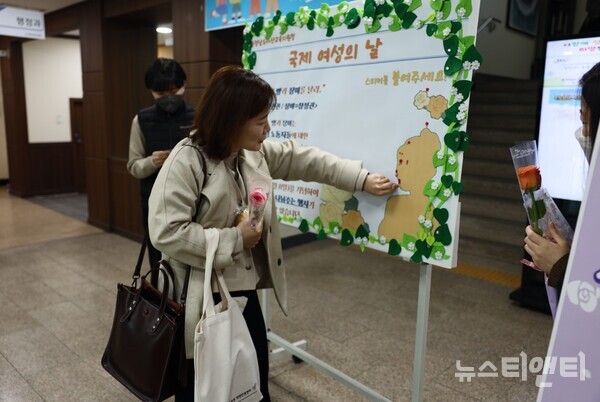 한 여성이 세계 여성의 날 기념행사에 마련된 포드판에 장미 스티커를 붙이고 있다. / 아산교육지원청 제공