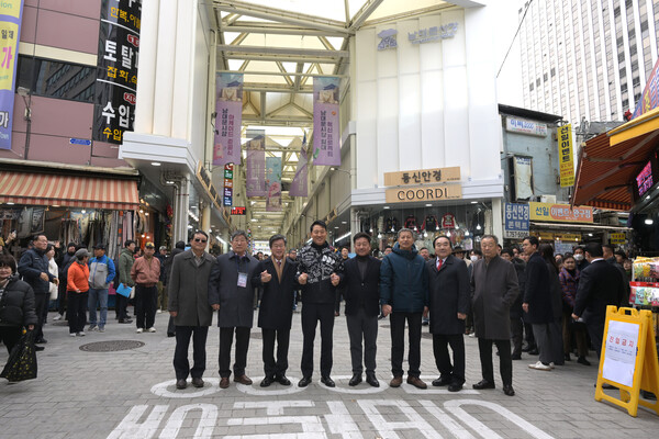 남대문시장 중심가로에 새롭게 조성된 135m 아케이드 앞에서 김길성 중구청장과 관계자들이 준공을 기념하며 기념촬영을 하고 있다. / 서울중구청 제공