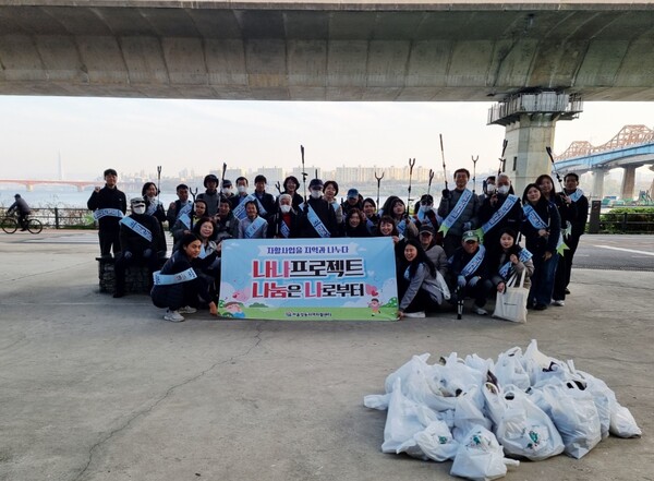 성동지역자활센터와 자활참여 주민, 구청 직원 등이 한강변에서 ‘나나 프로젝트–우리동네 쓰담쓰담’ 환경정화 활동을 진행한 뒤 단체 기념촬영을 하고 있다. / 성동구청 제공